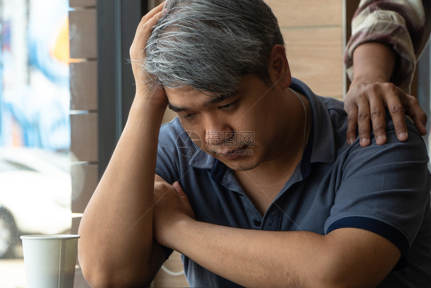 40岁压力和疲劳的中年亚洲男子正坐在快餐厅里有朋友站在后面鼓励帮助和的概念20世纪8年代到9郁闷快速地酒吧图片