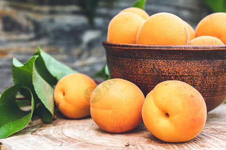 杏子熟了抗氧化剂木制的美味熟杏放在碗里旁边是木桌上的绿叶收成背景