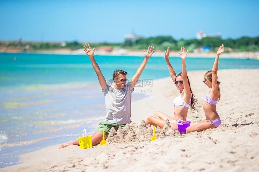 喜悦父亲和孩子在热带海滩玩沙子的家庭父亲和孩子在热带海滩制作沙堡家庭玩滩具年轻的异国情调图片