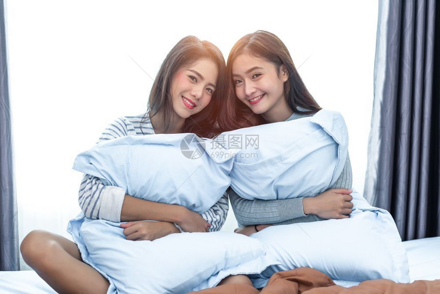 两名亚洲女者在卧室中美人概念下快乐的生活方式和家庭甜蜜的主题Cushion枕头元素和窗口背景床愉快伙伴图片
