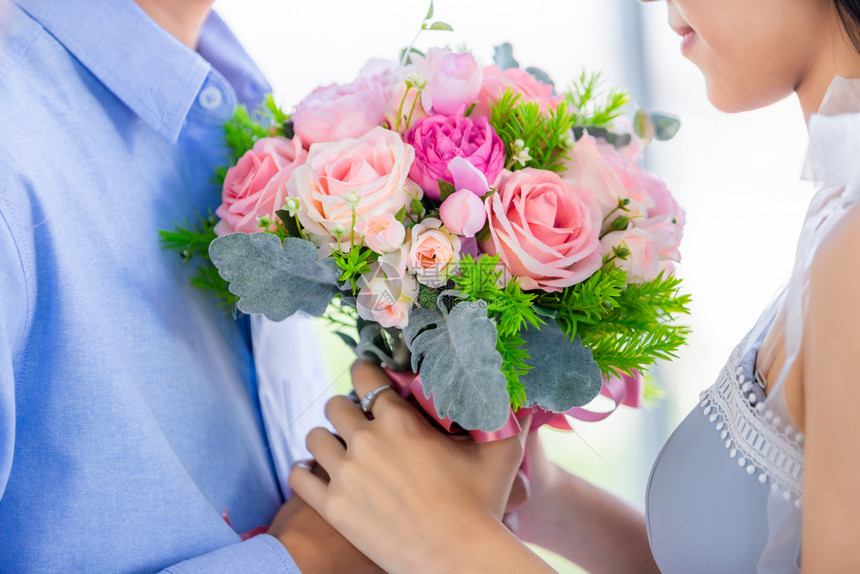 年轻的迷人感情结束亚裔年轻快乐的情侣握着红和粉玫瑰花束在午餐后厅里做饭时的背景图片