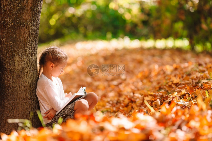 秋天蹲在树下看书的小女孩图片