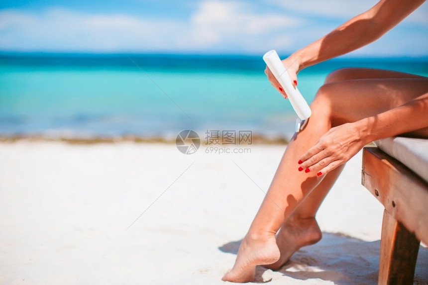 关心保湿剂海滨女人用手从太阳霜瓶子背景下打防晒霜海上女孩用手擦防晒霜瓶子背景下松绿水图片