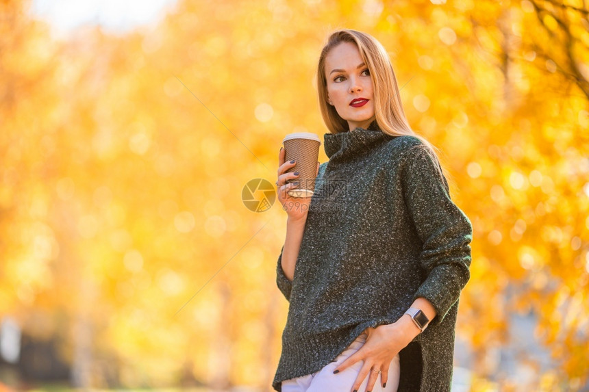 秋天森林里端着咖啡的女性图片