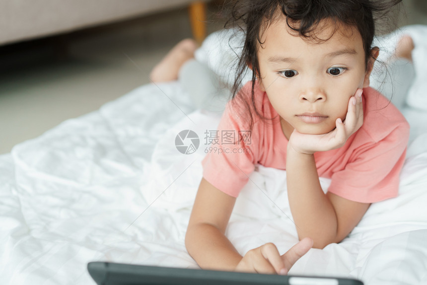 采用亚洲女孩正在网上媒体观看令人兴奋的视频小女孩用平板电脑观看家庭娱乐录像iinfoFlickr放松快乐的图片