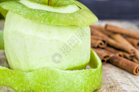 削水果皮新鲜的剥开绿苹果与整个香味肉桂一起躺在黑木桌上关闭天然水果皮绿色苹调味颜背景