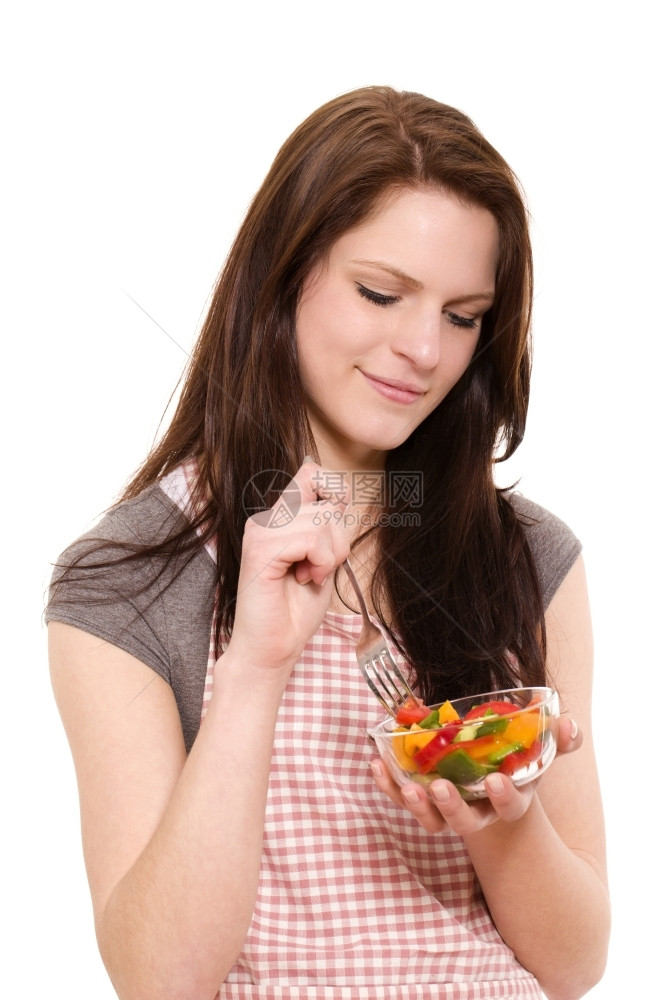围裙胡椒钟带着笑脸的色拉微着美丽的女人在白色背景下吃混合沙拉图片