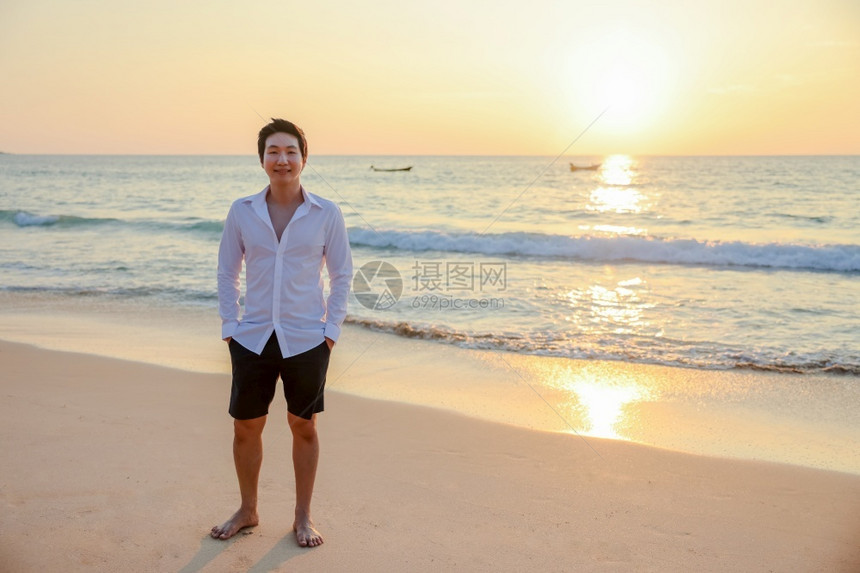 肌肉发达人们感的在海滩上快乐亚洲年轻男人看着摄影机旅行度假暑日落背景的假期图片