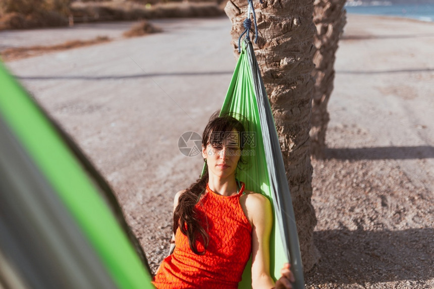 女人躺在海边棕榈树之间的吊床上好闲暇请享用图片