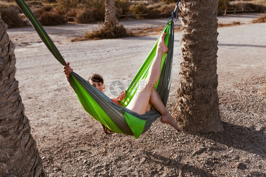 美丽天空女人躺在海边棕榈树之间的吊床上好图片