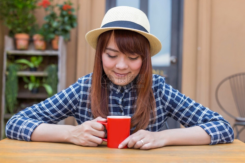 穿着帽子的女士坐在户外喝热饮放松快乐的美丽红色图片