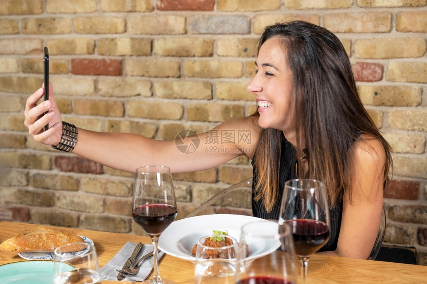 愉快年轻的美丽女子在餐厅吃饭时拍自照片高品质的相美丽年轻女子在餐厅吃东西时拍自照片她正在摄自照片淑女图片