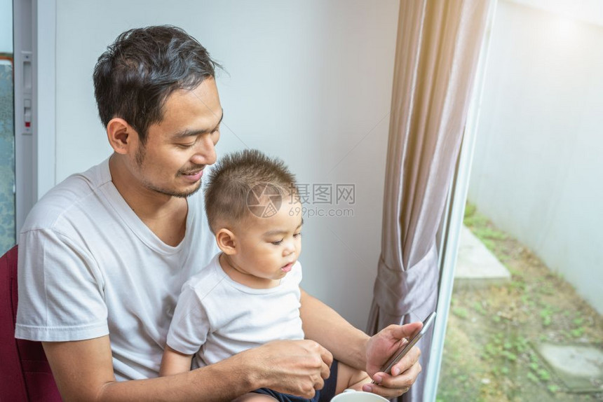 亚洲父子在家中一起使用智能手机图片