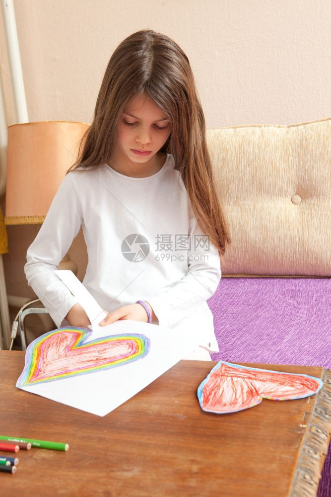 小女孩正在为母亲日或父情人节的生画红和多彩的心天色图片