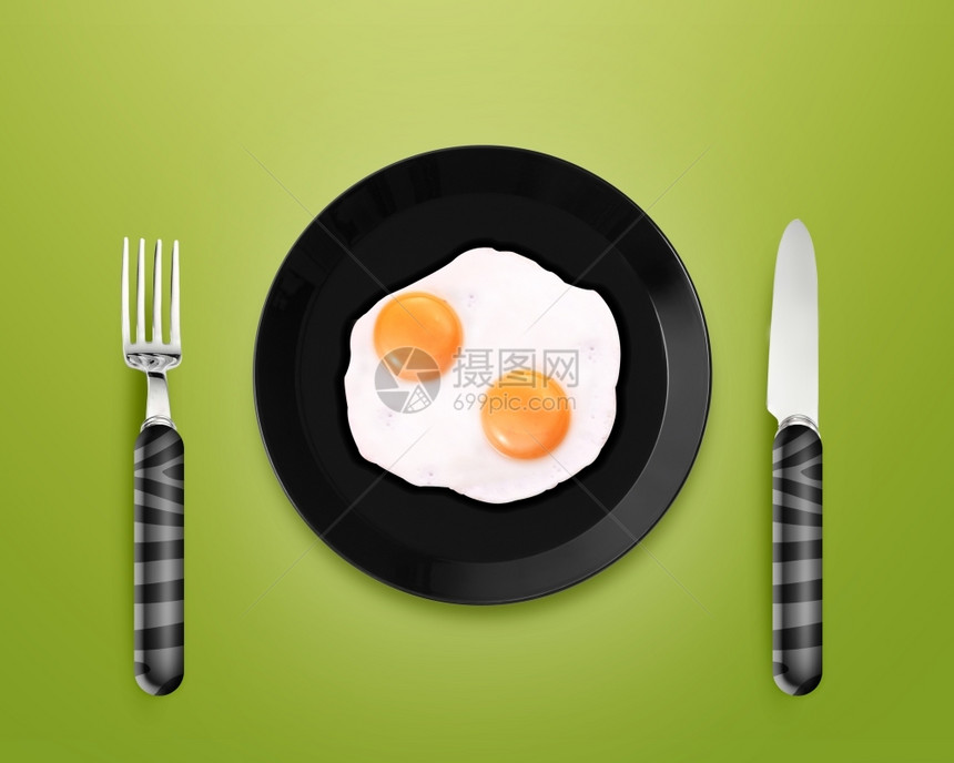 烹饪美食银刀和灰底叉之间黑色板块上两个煎蛋的顶部视图剪下图片