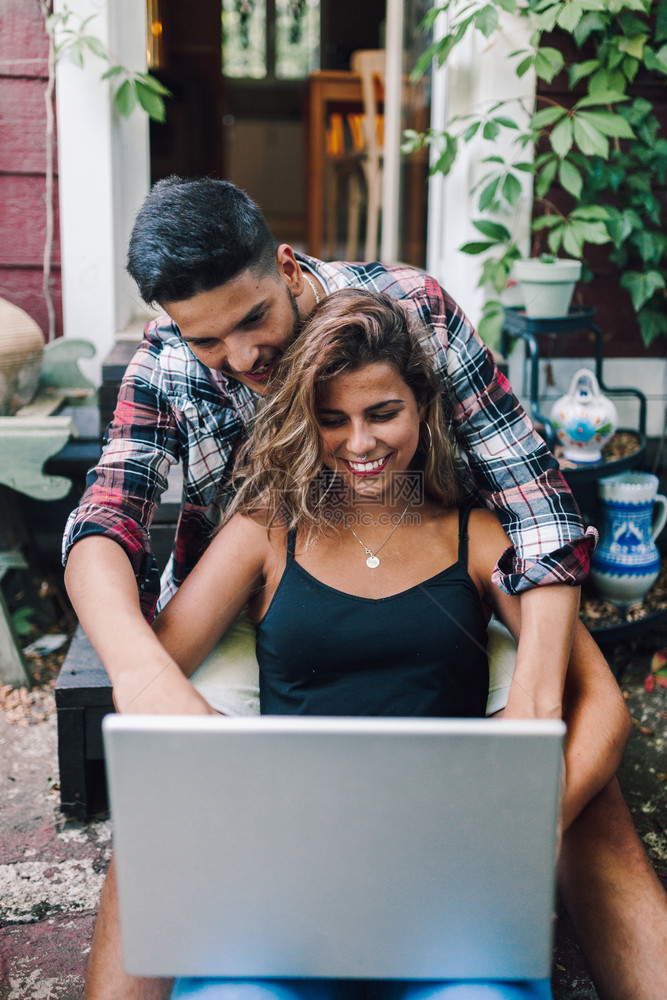 药片季节坐在木屋用笔记本电脑的阶梯中拥抱着一对微笑的年轻夫妇娱乐图片