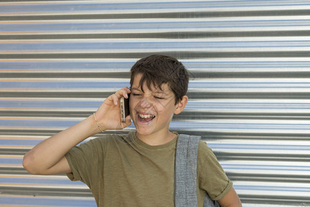 基本的快乐男孩使用手机背着包回到学校概念中来玩的开心男孩白种人电话图片