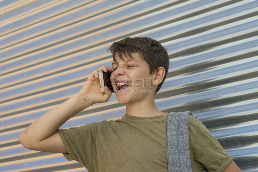 城市快乐男孩使用手机背着包回到学校概念中来玩的开心男孩现代人图片