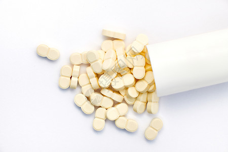 白色背景上从瓶子里出来的药丸物制造业图片