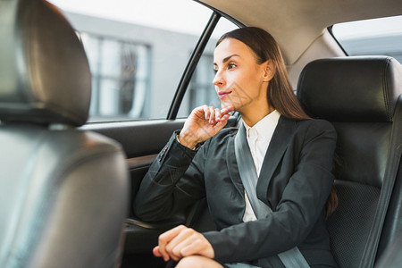 后座移动的商业女人乘车旅行时透过窗户看望转移图片