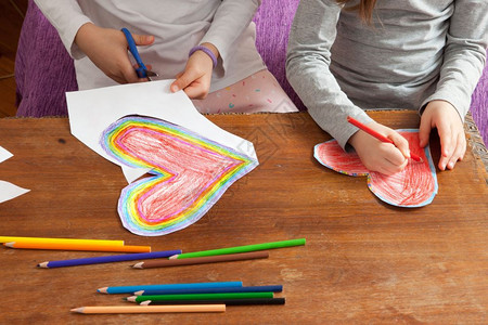 小女孩正在为母亲日或父情人节生画红和多彩的心胸男生妈们草图图片