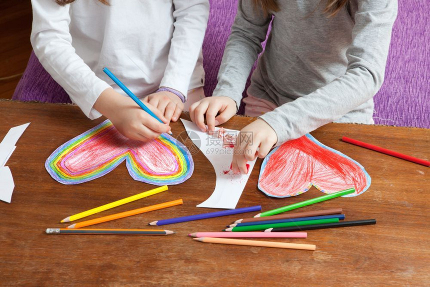小女孩正在为母亲日或父情人节生画红和多彩的心胸创造力假期幼稚的图片