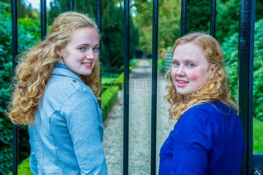 两个天主教的少女姐妹看着花园的篱笆向后仰望青少年门户网站酒吧图片