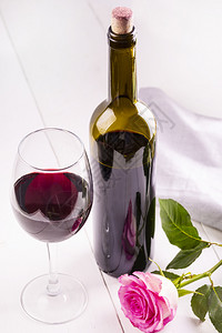 花瓣奢华酒瓶装软木塞和白桌上的玫瑰酒吧图片