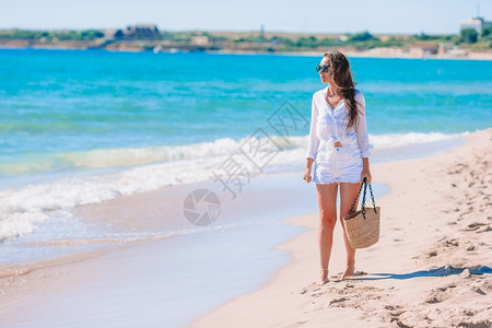 热带海滩上白色沙的年轻美女松弛士太阳图片