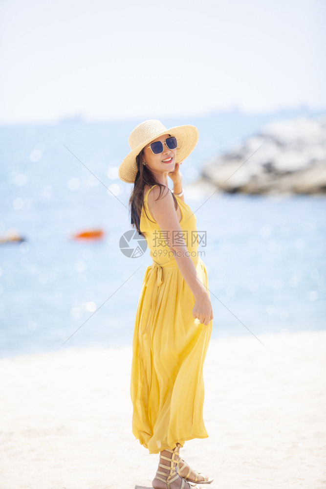 亚洲人身着黄色衣服在夏日Vacaitton海滩轻松放的美丽亚洲年轻女旅行时尚图片