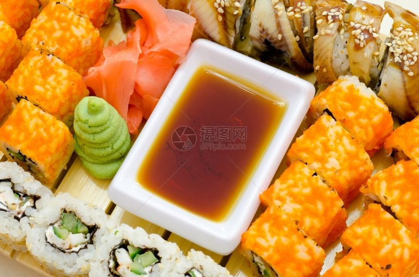 新鲜的有许多寿司卷配有黄酱姜汁和油生的图片