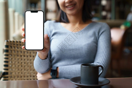 成人女士们坐在旅馆餐厅里放松一下开心地把电话看成白色空屏幕手数字的图片