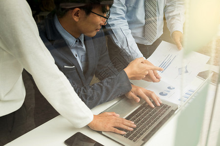 研究团队工作进程商企讨论人营销计划会议与办公笔记本电脑和财务文件数据一起放在桌面上的概念统计手背景图片