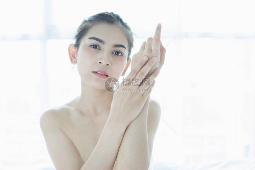 服用浴室一位使皮肤护理产品润湿剂或滑的美丽女亚洲人在手中照料她的干乳油奶人们图片