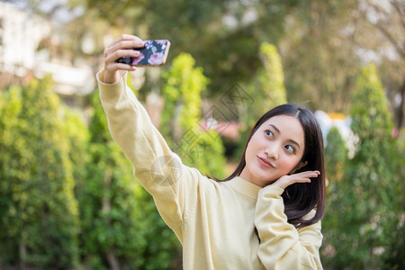 文化他们的可爱亚裔女正在使用手机取自拍和在家中花园笑肖像图片