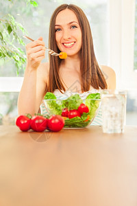 笑着的caucasian女人吃沙拉的照片家在室内节食图片