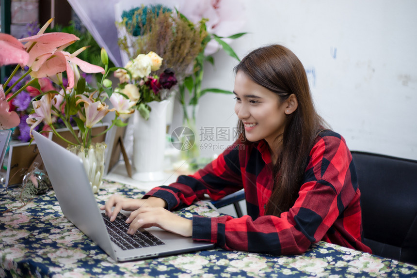 微笑园丁数字的使用笔记本在花店工作的亚洲妇女花商图片