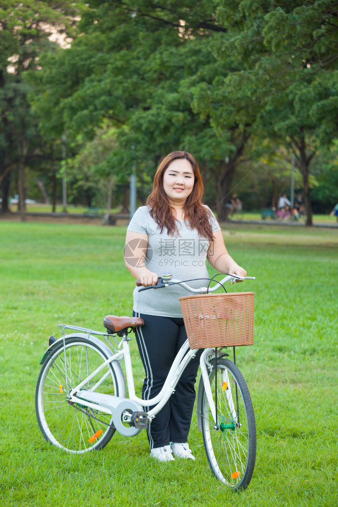 加可爱的快乐肥胖亚洲女人在公园露天用自行车超重图片