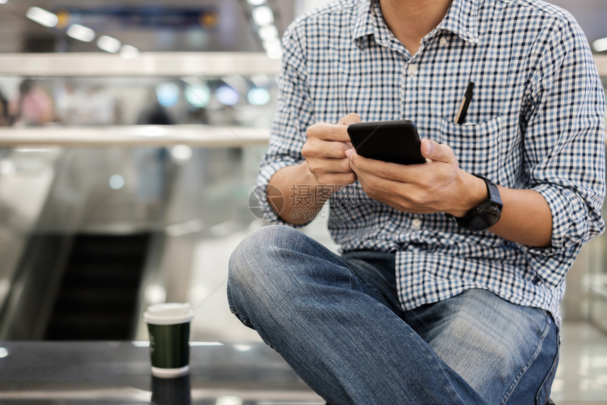 在饮热咖啡生意活方式技术和社交媒体网络概念之间使用智能手机坐着青年临时散工和在喝热咖啡业技术和社交媒体网络概念之间使用智能手机短图片