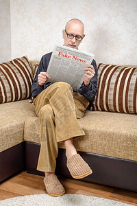 霍雷兹姆沙新闻业一名戴眼镜的男人坐在家里沙发上看报纸导假新闻冒消息LoremImpsum文本小报公背景