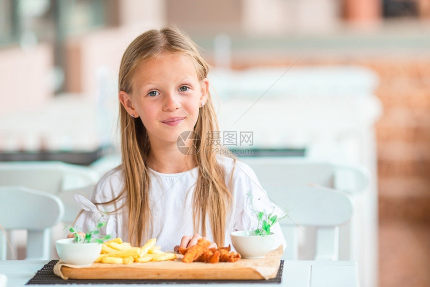 饥饿的孩子在户外咖啡厅吃早饭的可爱女孩在户外咖啡厅吃晚饭的可爱小女孩刀图片