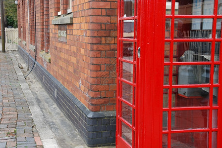 经典的上市背景型的红色电话亭和砖墙建筑红式电话亭和砖墙优质的图片