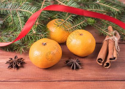 松树星作品3个橘子和三根肉桂棒在fir树枝下图片