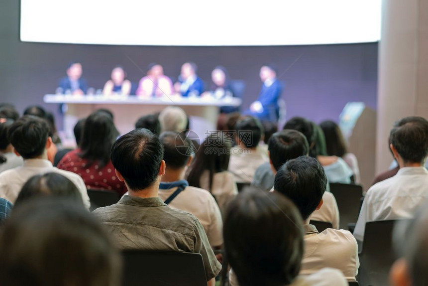 曼谷模糊在有发言者集思广益和谈论舞台商业和关于投资概念的教育会议厅或研讨上的观众看场或研讨上发言者们正在就投资概念进行集思广益和图片