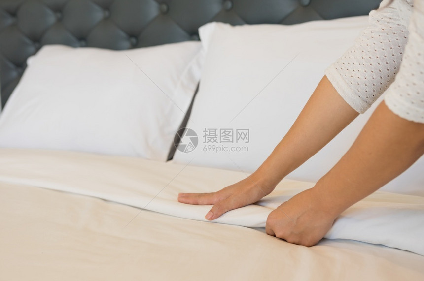 折叠淋浴家年轻的旅馆女青在干净的房间里准备床上有干净白毯子卧室有枕头和床单早上睡衣用软毛巾图片