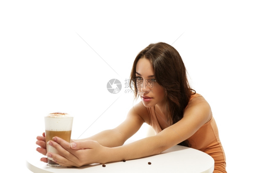 泡沫杯子年轻女拿着铁玛奇朵咖啡在桌子的另一边年轻女子拿着铁玛奇朵咖啡在桌子的另一边白色背景年轻的图片