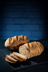 自制黑桌和蓝砖背景上的Gluten免费多黑面包自然乡村图片