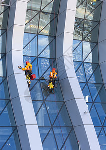 窗户清洁工在现代摩天大楼的玻璃面罩上工作洗攀登手动的图片