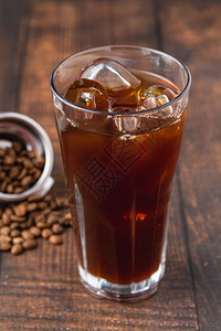 杯子黑暗的棕色一杯冰美式咖啡块放在店的木桌上图片