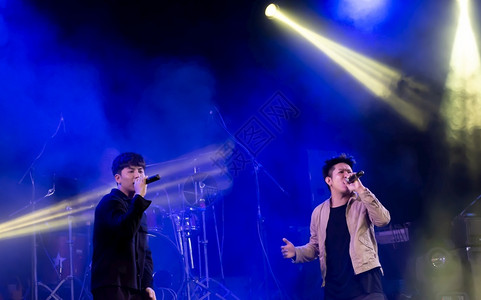 青年亚洲男歌手在舞台娱乐和音会概念上展示了他们的表演风光电聚灯图片